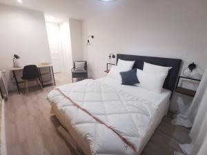 een slaapkamer met een groot wit bed en een bureau bij Villas Chapu in Fontainebleau