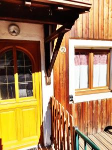 a yellow door and windows on a wooden building at Gîte LaO in Gérardmer