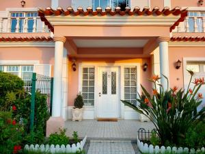 een roze huis met een witte voordeur bij Villa Shardana B&B in Sesimbra