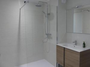 La salle de bains blanche est pourvue d'une douche et d'un lavabo. dans l'établissement VILLA GEORGES, au Grau-du-Roi