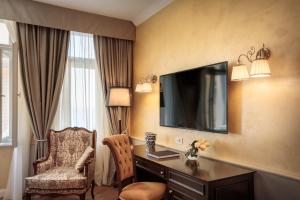 a hotel room with a desk and a television on the wall at Villa Abbazia - Liburnia in Opatija