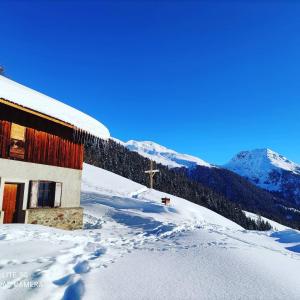 una iglesia en la nieve junto a una montaña en Residence Alice, en Celledizzo