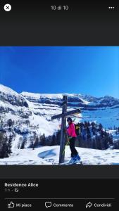 una persona en esquís junto a un cartel en una montaña en Residence Alice, en Celledizzo
