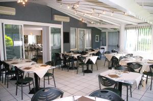 a dining room with white tables and chairs at Hôtel du Moulin à Vent in Vénissieux