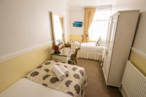 a bedroom with a bed and a desk and a mirror at Summerlands Guest House in Torquay