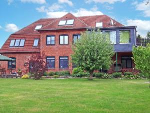 a large red brick house with a green yard at Ferienwohnungen direkt am See in Ventschow