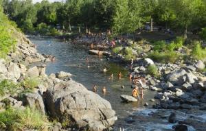 a group of people swimming in a river with rocks at Los Arbolitos Cabañas y Aparts in Santa Rosa de Calamuchita