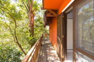 an orange house with a balcony with trees at Dubai Bungalows Bombinhas in Bombinhas