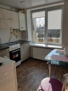 eine Küche mit einem Herd, einem Tisch und einem Fenster in der Unterkunft Apartament in chirie Moldova or.Soroca in Soroca