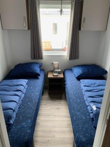 twee bedden in een kleine kamer met een raam bij Camping de Zandput - 604 in Vrouwenpolder
