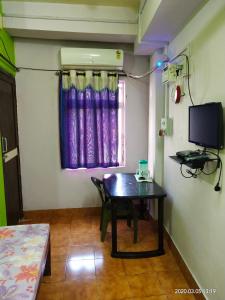 a small room with a table and a tv at AMINA LODGE in Port Blair