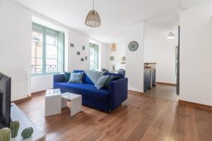 My Colmar Homes - Le XIII في كولمار: غرفة معيشة مع أريكة زرقاء ومطبخ