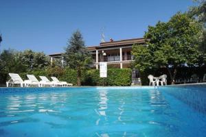 a swimming pool with white chairs and a house at Pool-Apartments Porec (4400) in Poreč