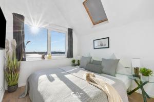 a white bedroom with a bed and a window at Slienblik in Olpenitz