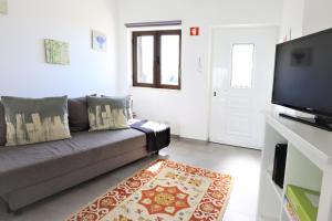 a living room with a couch and a flat screen tv at Vila - Mar - Private outdoor Jacuzzi - wifi & airco - by bedzy in Albufeira