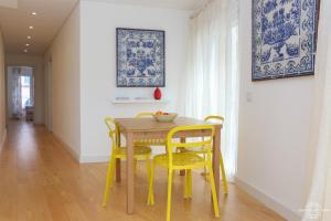 リスボンにあるAzulejos' Charming Apartment with Terrace 2 by Lisbonne Collectionのダイニングルーム(テーブル、黄色い椅子2脚付)
