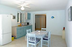 een keuken met een tafel en stoelen en een witte koelkast bij Beachfront Apartment in Tri Porte, with sea view, terrace, air conditioning, WiFi 5208-2 in Potirna