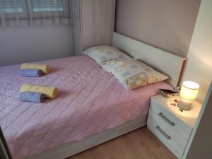 a small bedroom with a bed with pink sheets and pillows at Apartment in Lopar with Terrace, Air conditioning, Wi-Fi, Washing machine (4619-1) in Lopar