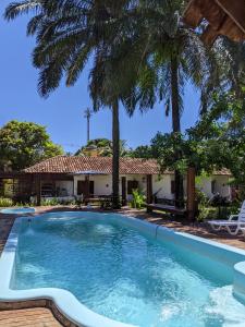 a swimming pool in front of a house with palm trees at Pousada Nova Papa Terra in Itacaré