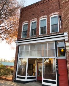 ein Backsteingebäude mit einer roten Tür und Fenstern in der Unterkunft Suites at 249 in Culpeper