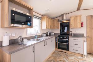 ポックリントンにあるSquirrel Lodge with Hot Tubのキッチン(木製キャビネット、シンク、電子レンジ付) +10枚の写真