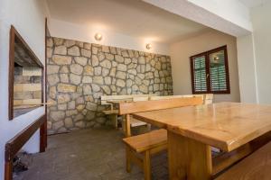 a room with wooden tables and a stone wall at Beachfront Apartments Lopar (4419) in Lopar