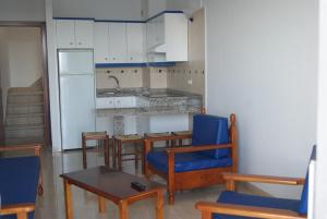 a kitchen with blue chairs and a table and a counter at Apartamentos Los Saltos in La Restinga