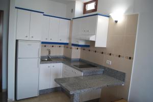 una cucina con armadietti bianchi e frigorifero di Apartamentos Los Saltos a La Restinga