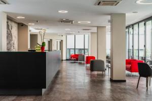 セグラーテにあるFasthotel Linateの赤い椅子とカウンター付きのオフィスロビー