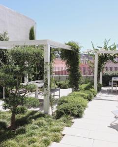 een tuin met witte stoelen en een pergola bij Destino Lisboa Apartments in Lissabon