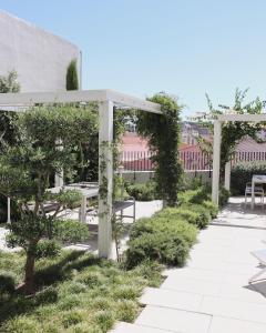 un jardín con sillas blancas y pérgola en Destino Lisboa Apartments, en Lisboa