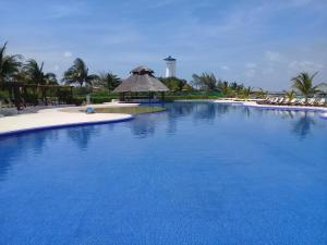 a large blue swimming pool with a lighthouse in the background at Swim the Caribbean & Work with a View in Cancún