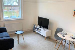 a living room with a television and a table and chairs at Coastal Corner in Mundesley