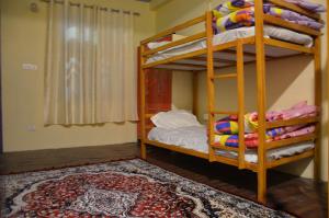a bedroom with two bunk beds and a rug at The Birds Hostel, Dalhousie in Dalhousie