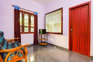 een kamer met een rode deur en een stoel en een spiegel bij CARMEL HOME STAY in Munnar