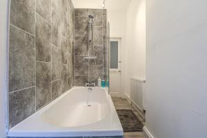 a white bath tub in a bathroom with a shower at Largs Coastal Apartment in Largs