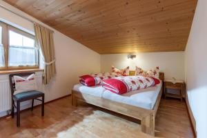 Un dormitorio con una cama con almohadas rojas y una silla en Ferienwohnung Gasteiger, en Steinberg am Rofan