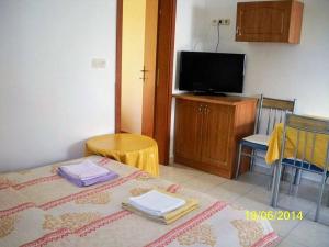 Cette chambre comprend un lit, une télévision et des chaises. dans l'établissement Apartment in Lopar with Balcony, Air condition, WIFI (4224-1), à Lopar