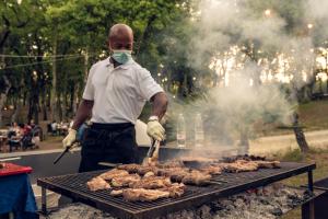 a man is cooking meat on a grill at Luxor Chianti Glamping village in Castellina in Chianti