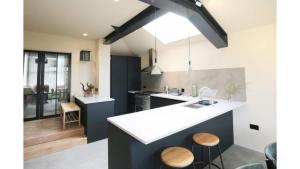 a kitchen with a sink and a counter with stools at Pass the Keys Stunning, Brand New 3BR Home - Central Oxford in Oxford