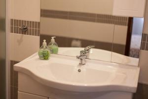 W łazience znajduje się umywalka z lustrem i butelki mydła. w obiekcie Large Terrace Apartment in Omisalj 3623-3 w mieście Omišalj +21 zdjęć
