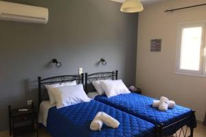 two beds in a bedroom with blue sheets and white pillows at Rodanthy I in Katelios