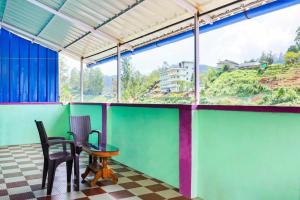 een kamer met 2 stoelen, een tafel en een raam bij CARMEL HOME STAY in Munnar