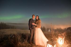 a bride and groom posing for a picture at night at Aurora Borealis Observatory in Silsand