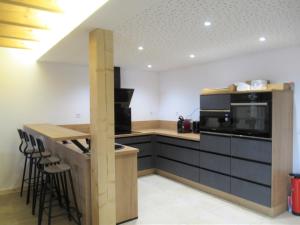 a kitchen with black cabinets and a counter with stools at La Ferme du Panorama et Spa in Ventron