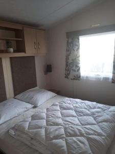 a bedroom with a large white bed with a window at Luxe vakantiechalet met omheinde tuin Bredene 6pers (2572) in Bredene