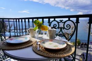 een tafel met borden en kopjes op een balkon bij Mavi Apartments in Piano di Sorrento