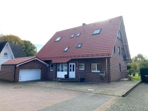 une maison en briques avec un toit rouge et un garage dans l'établissement Ferienwohnung Olli Koch, à Reken