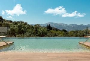 uma piscina de água com montanhas ao fundo em Hacienda Fresneda María by Charming Stay Adults Recommended em Villanueva del Rosario