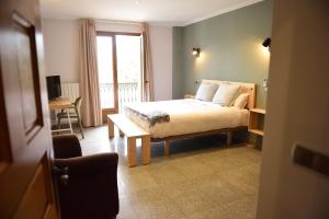 1 dormitorio con cama, mesa y ventana en Hotel Vijanera, en Galizano